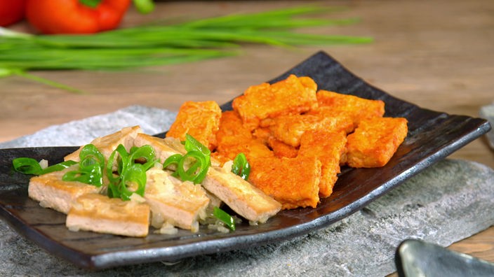 Der geschmorte Tofu ist auf einem Teller angerichtet mit etwas Frühlingszwiebeln.