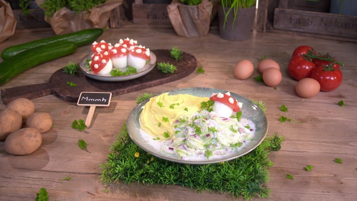 Das Bild zeigt Kartoffelpüree mit Gurkensalat und lustigen Fliegenpilz-Eiern.