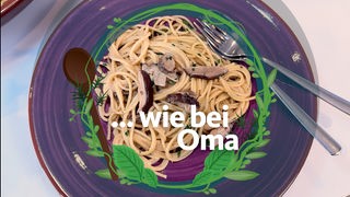 ein lilafarbener Teller, darauf liegen Spaghetti mit einer Steinpilz-Sahne-Sauce. Darauf liegt ein Logo der Reihe "... wie bei Oma" mit einem Schriftzug.