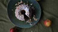 Apfel-Gugelhupf ungeschnitten auf einem Teller aus der Vogelperspektive fotografiert.