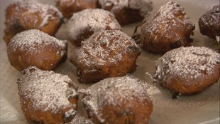 Mehrere mit Puderzucker bestreute Apfel-Püfferkes auf einem Blech