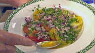 Tomatensalat mit Zwiebel-Petersilien-Marinade auf einem tiefen Teller angerichtet