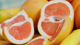 Das Bild zeigt eine aufgeschnittene und mehrere andere Grapefruits.