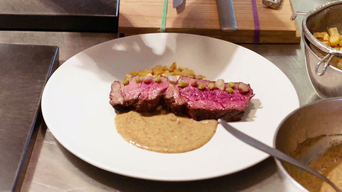 Das Bild zeigt Yak-Steaks mit gewürfelten Pastinaken, karamellisierter Sahne und Zwiebel-Pickles.