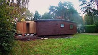 Auf dem Bild sieht man ein Holzchalet auf einem Campingplatz