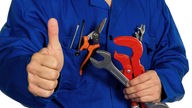 Das Bild zeigt einen Handwerker mit Werkzeug, der mit dem Daumen nach oben zeigt. 