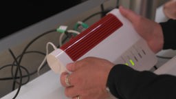 Das Bild zeigt eine Person, die einen W-LAN-Router in ihren Händen hält.