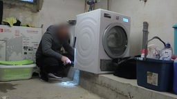 Das Bild zeigt eine Waschmaschine und einen Handwerker.