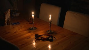 Zwei Kerzen auf Kerzenständern in einem dunklen Raum