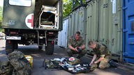 Bundeswehr bei Hilfsarbeiten, zwei Soldaten mit Fahrzeug;