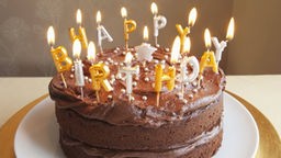 Schokoladenkuchen mit Kerzen in Form von "Happy Birthday"