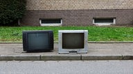 Zwei alte Fernsehgeräte stehen auf der Straße