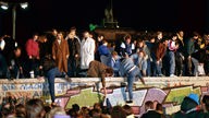 Nach der Öffnung der DDR Grenzen zum Westen stürmen Berliner aus beiden Teilen der Stadt die Mauer am Brandenburger Tor