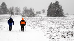 Spaziergänger wandern durch den ersten Schnee am Kahlen Asten im Sauerland