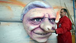 Der Düsseldorfer Karnevalsfigurenbauer Jacques Tilly nimmt den Pappkopf des emeritierten Papstes Benedikt XVI. von der Wand.