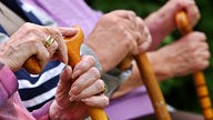 Senioren halten sich an ihren Gehstöcken fest