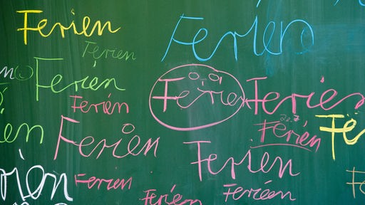 Schüler schreibt "Ferien" an eine Tafel