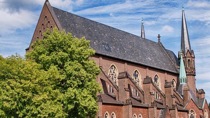 Seitenansicht von St. Marien Eschweiler, einer Kirche aus rotem Backstein vor blauem Himmel