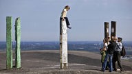 Maedchen sitzt auf einem Totempfahl und wird fotografiert auf dem Gipfel der Halde Haniel