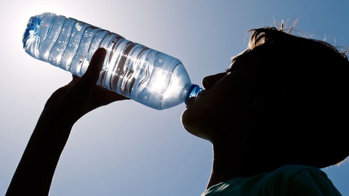 Symbolbild: Frau trinkt aus einer Wasserflasche in der Sonne
