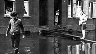 Kinder balancieren vor einem Mehrfamilienhaus beim Emscher-Hochwasser nach dem Zweiten Weltkrieg