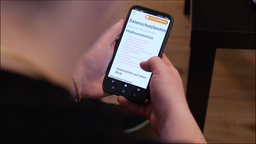 Jemand hält ein Smartphone mit der App der Bezahlkarte für Geflüchtete